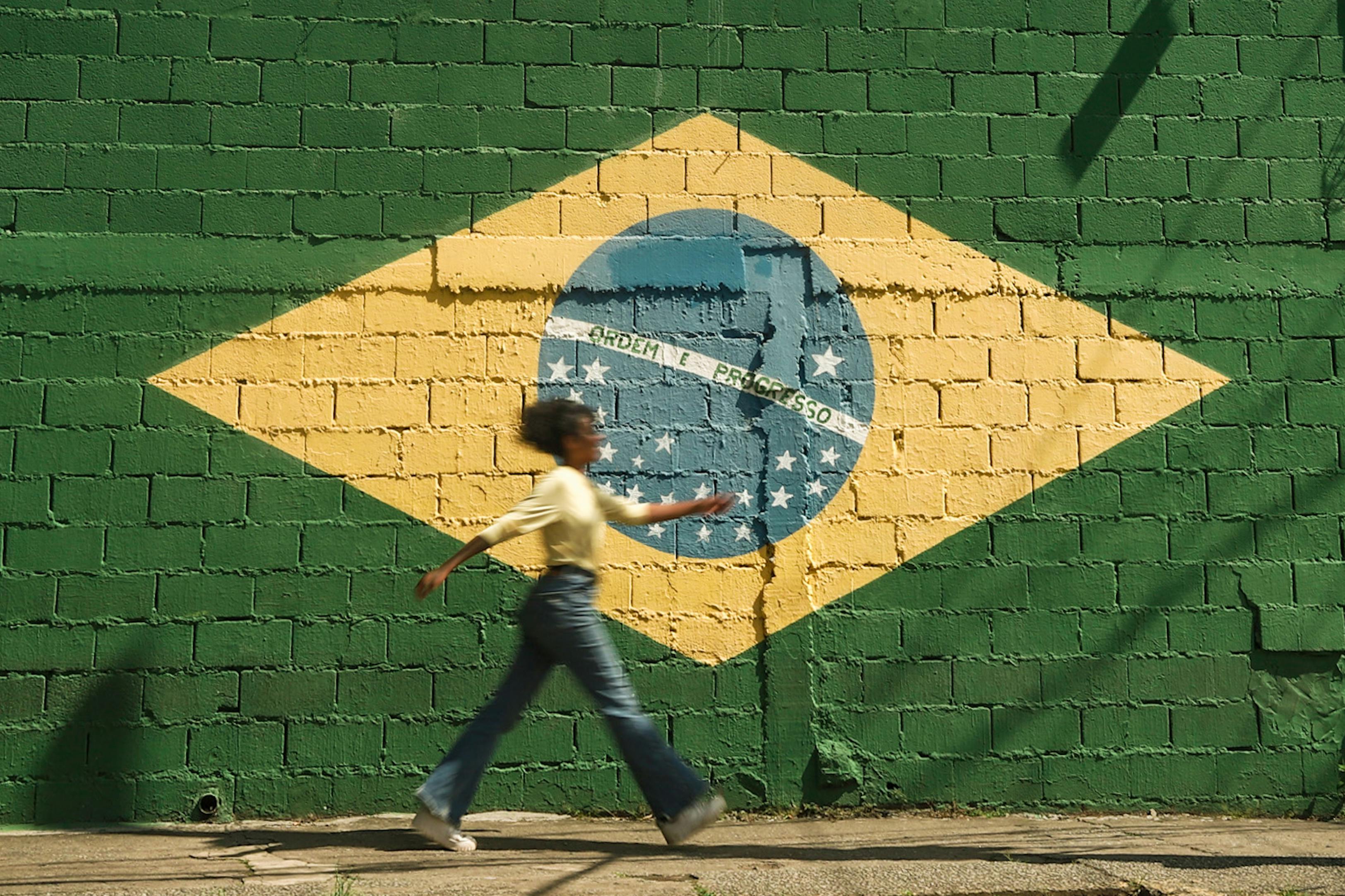 Girl walking infront of wall painting with Brazilian flag